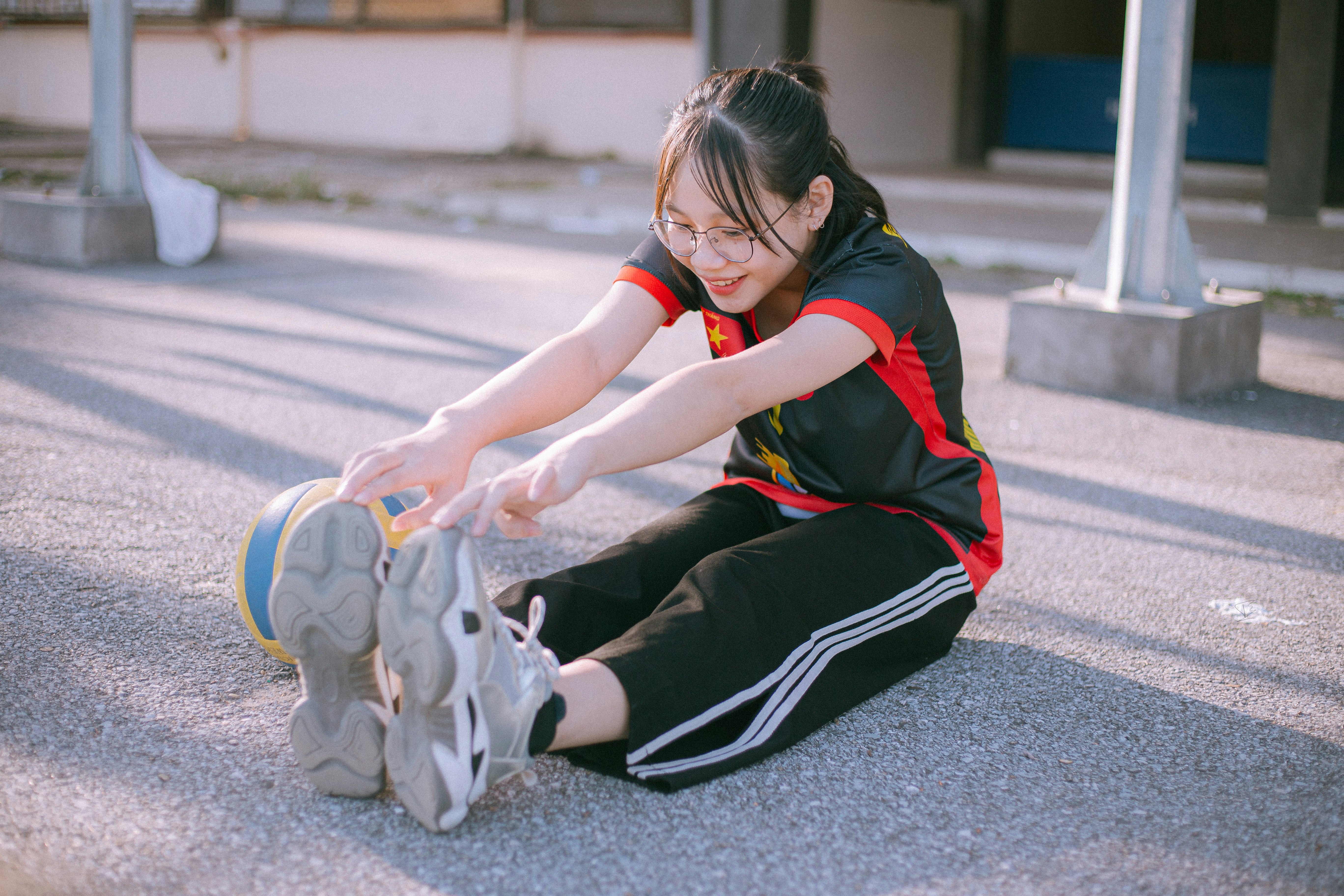 woman in black and red shirt and black pants sitting on gray concrete floor